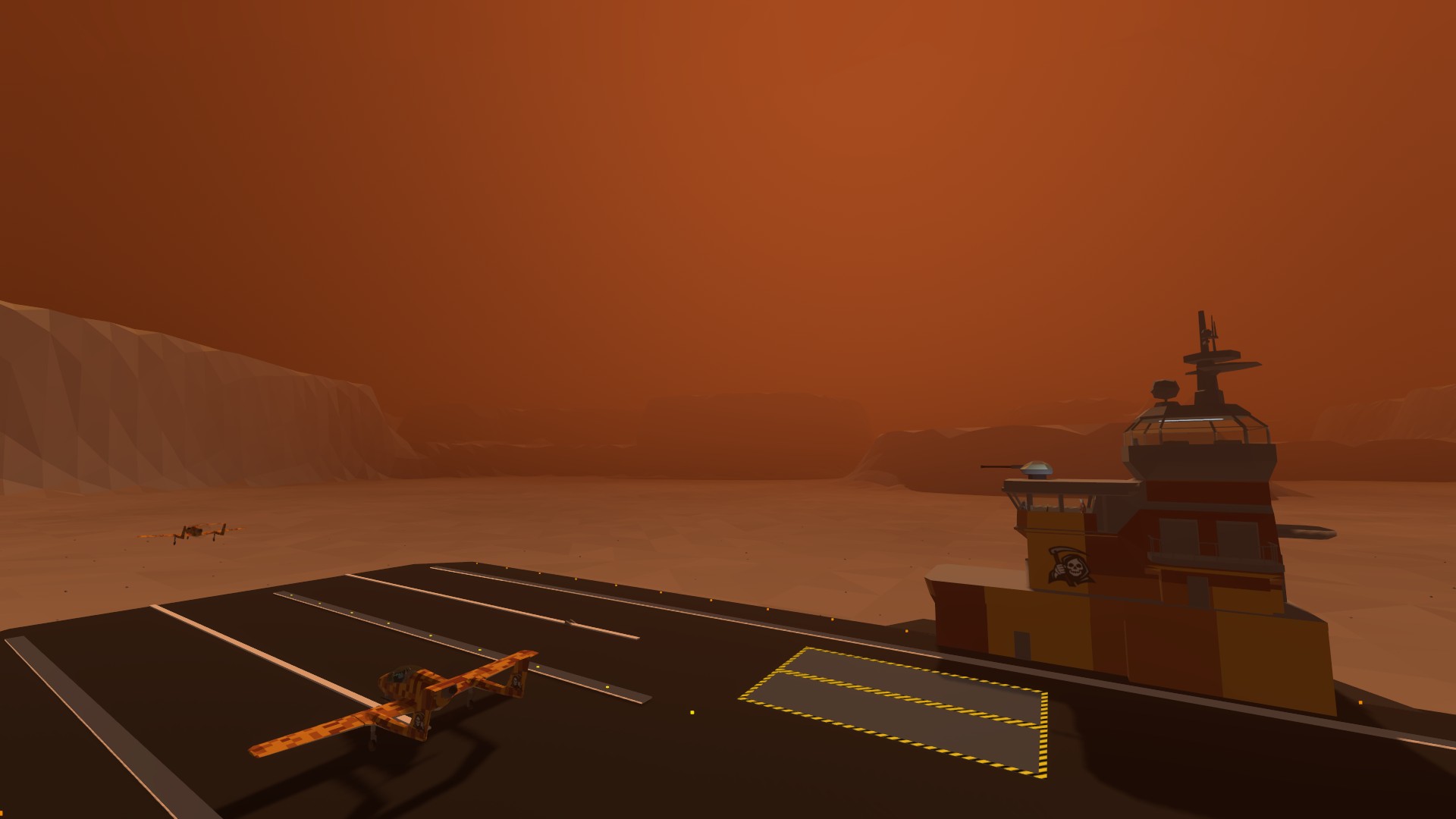 An aircraft on the land carrier’s flight deck beside its bridge and marked deck elevators, against an orange desert sky